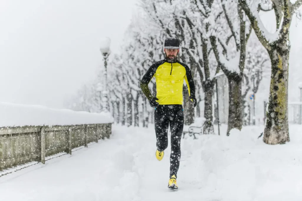 Man rennt im Winter durch Schneelandschaft, um Wim Hof Methode zu praktizieren.